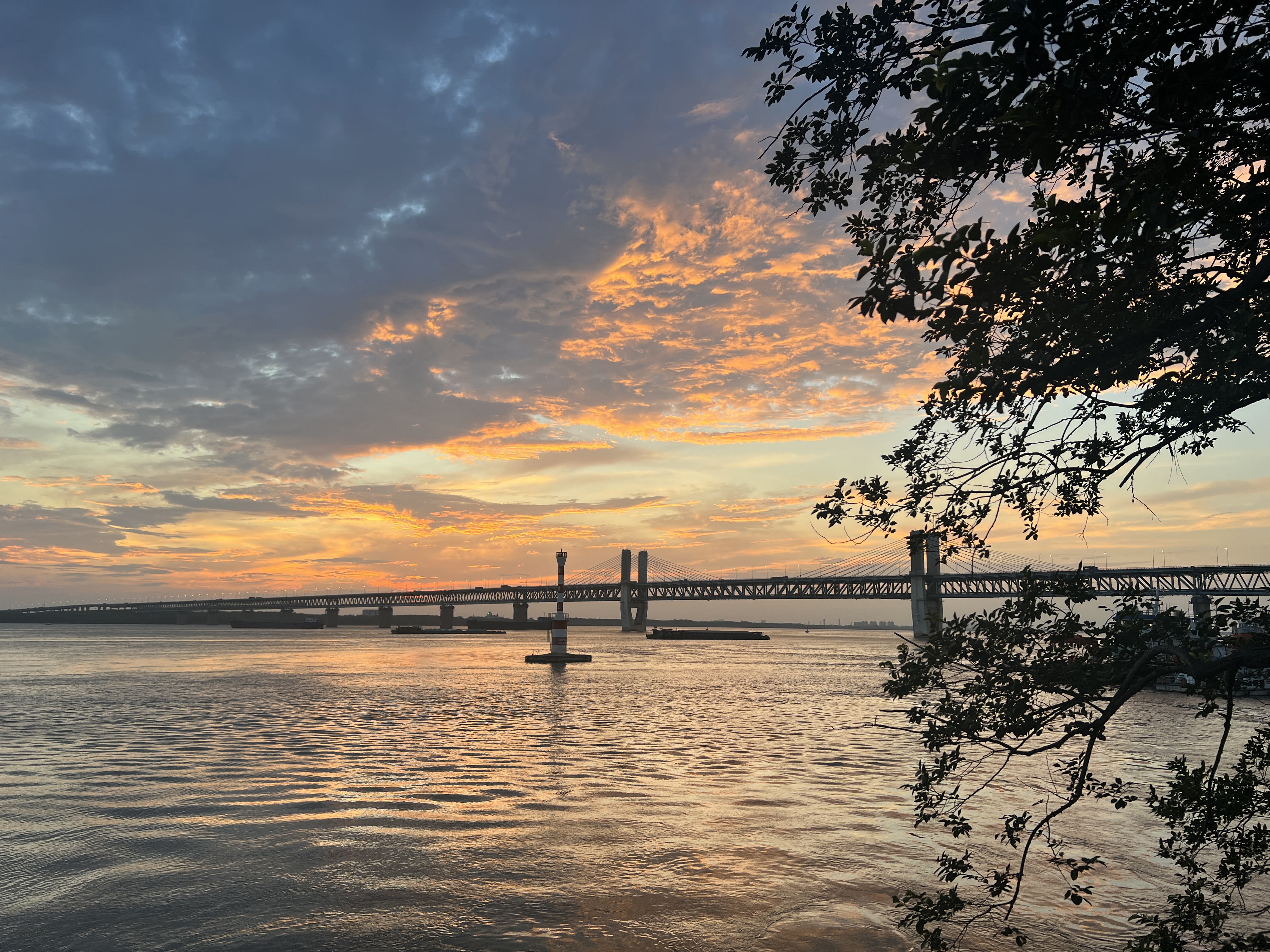 Sunset over a bridge with reflective waters and dramatic clouds.