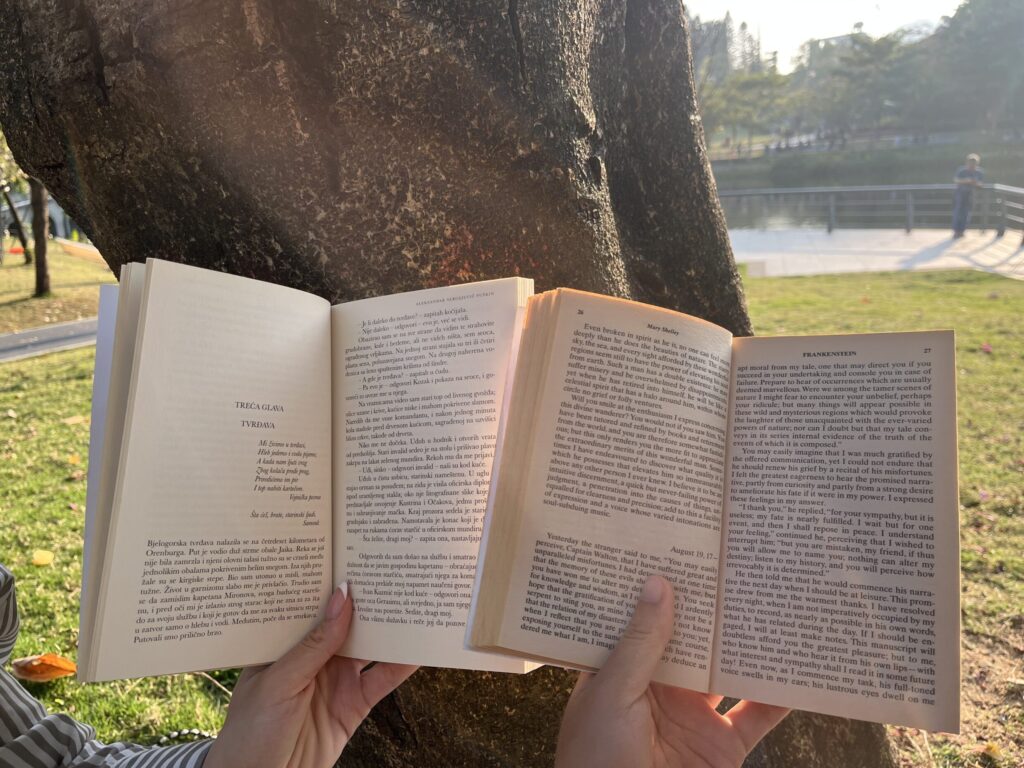 Two books leaning against a tree trunk.