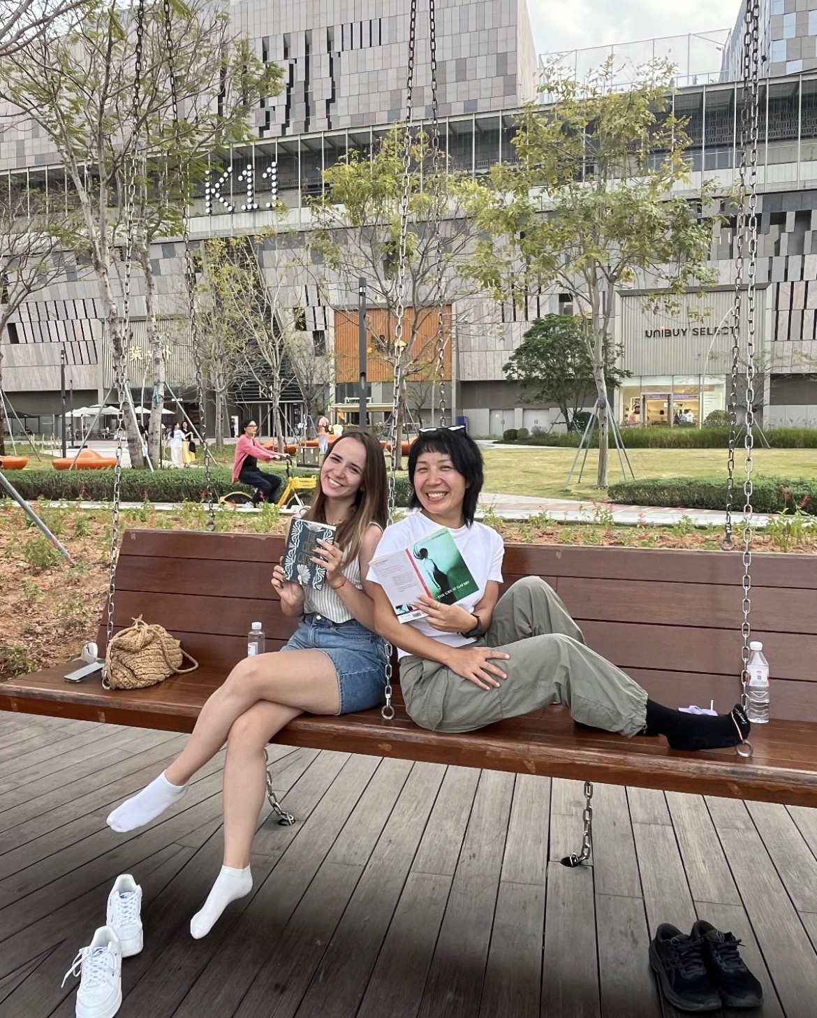 Two women holding books smiling to the camera.