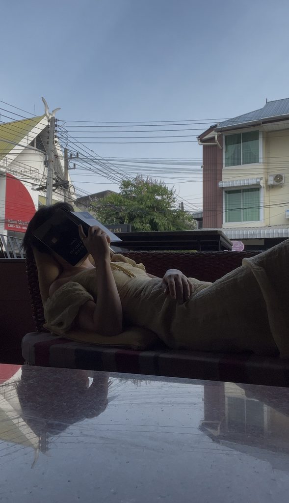 Falls resting on a long couch with a book covering her face