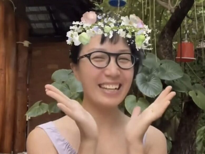 Smiling brightly while wearing a flower crown gifted during a live stream
