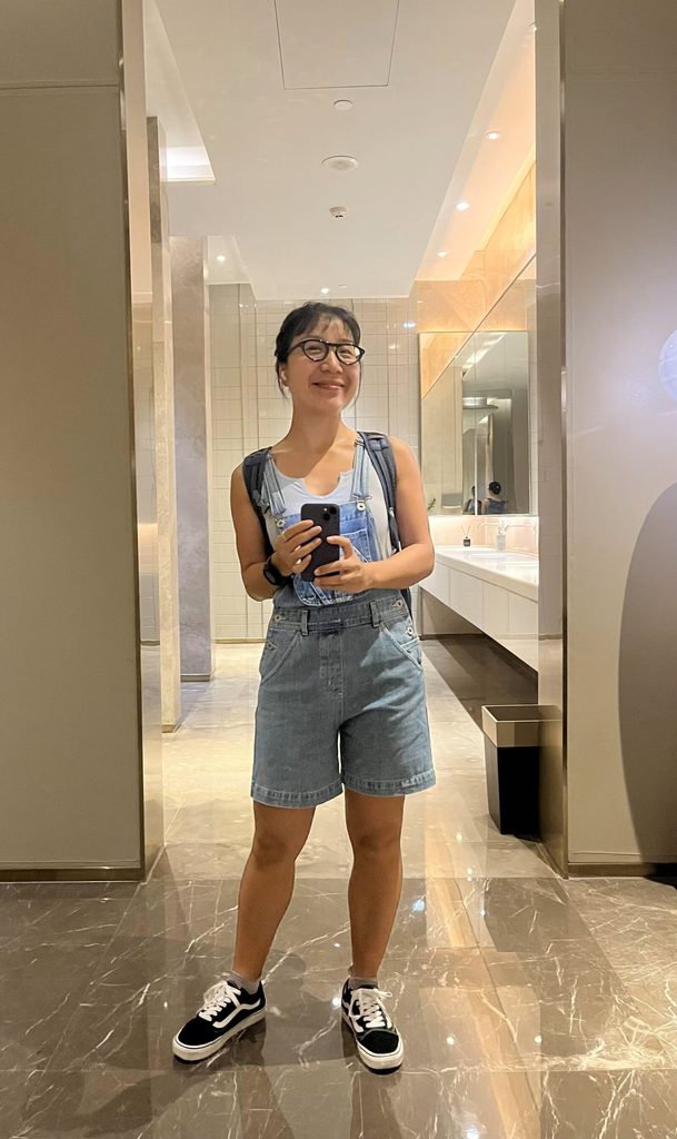 A full-body mirror selfie showing a person standing confidently in front of a mirror