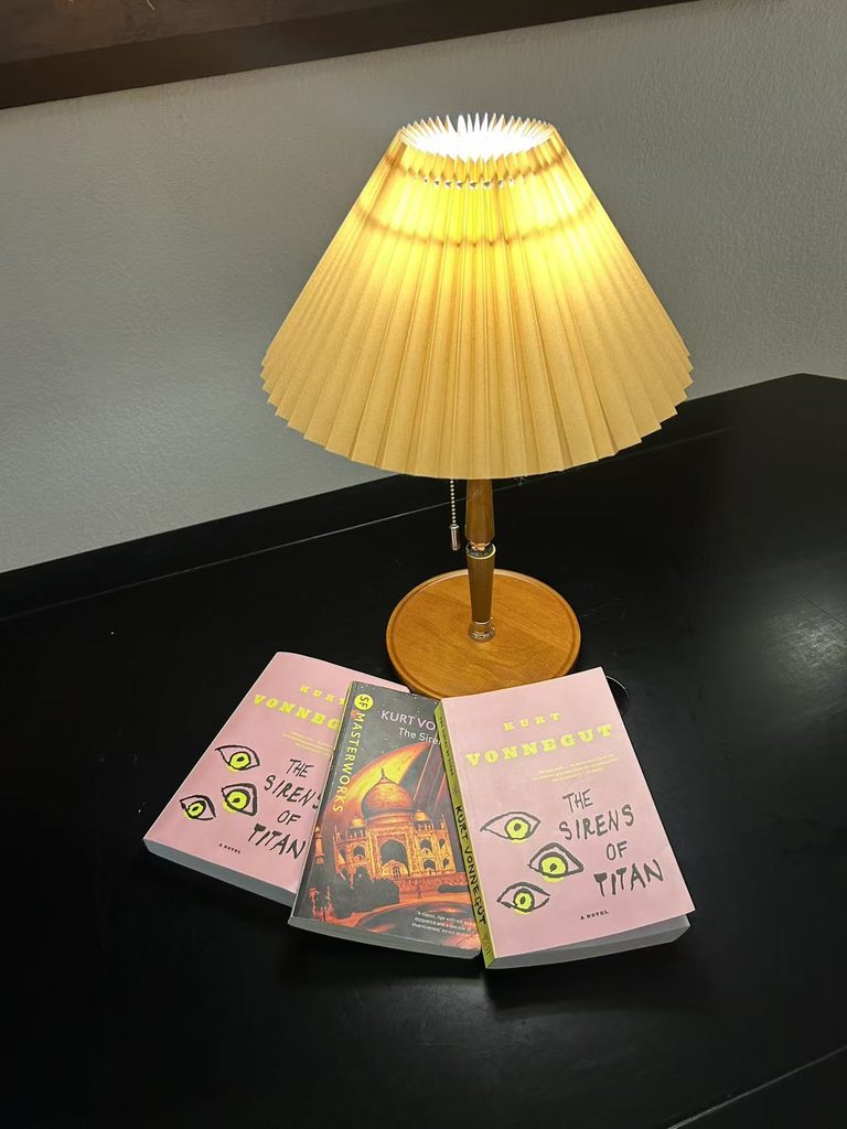 Three copies of The Sirens of Titan placed neatly under a soft desk lamp