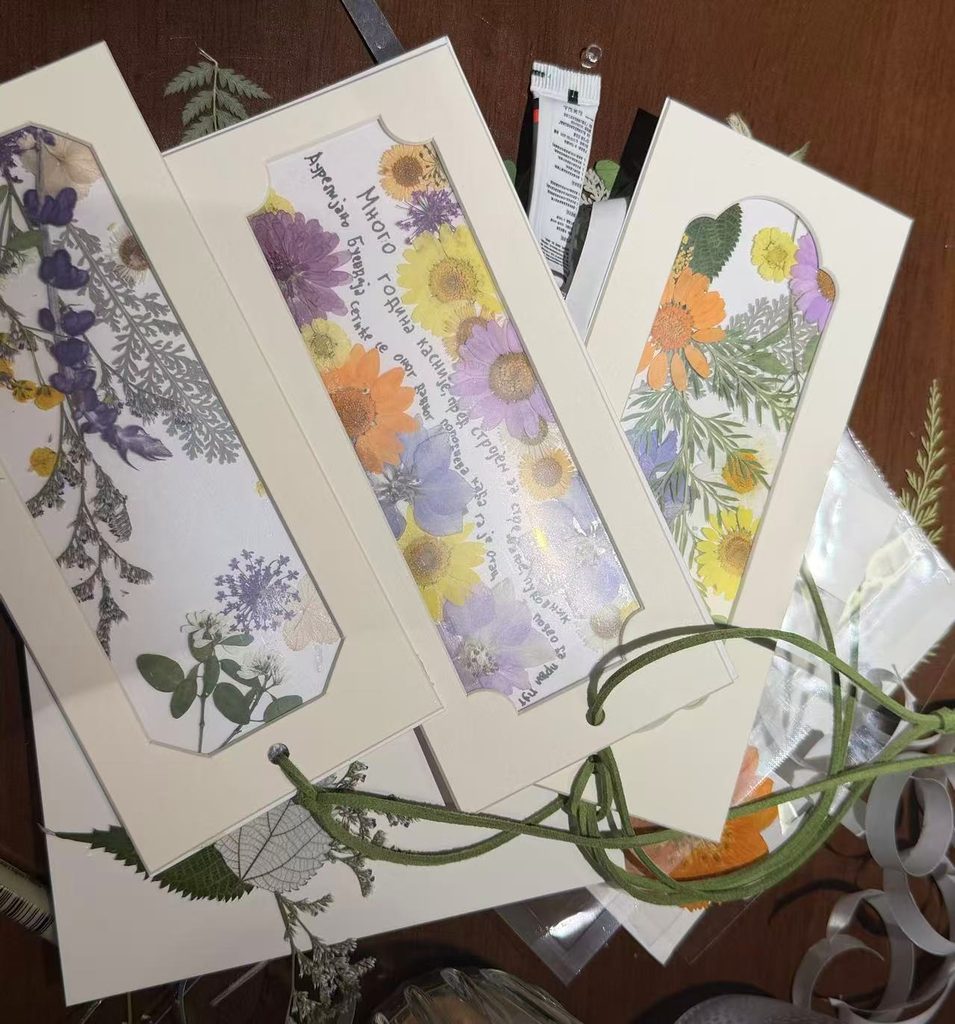 Handmade bookmarks created with dried flowers, arranged on a table as part of a creative book club activity.