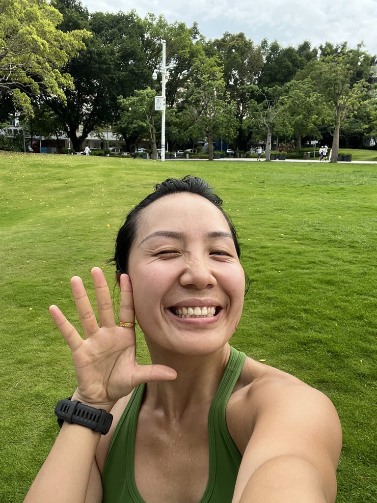 Falls smiling at the camera with a green top, standing in front of a green grass field