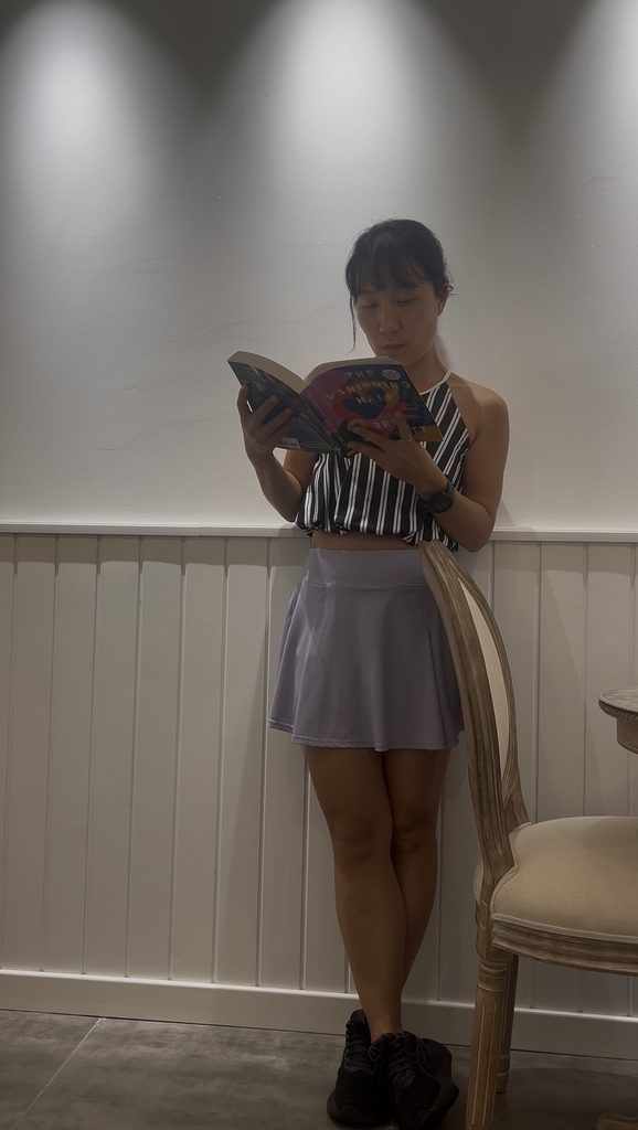 Falls standing against a wall reading The Vanishing Half during a Fallina Book Club meeting