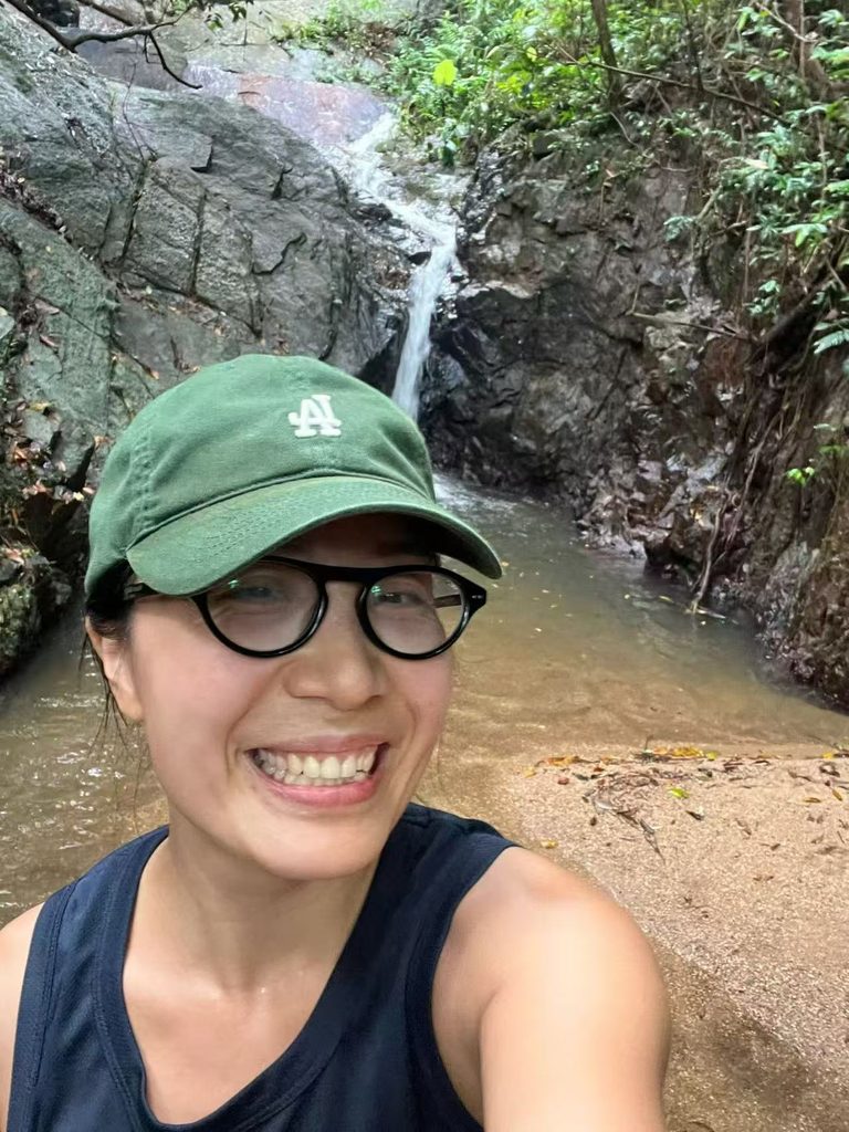 Falls smiling during a solo hike with a small waterfall in the background