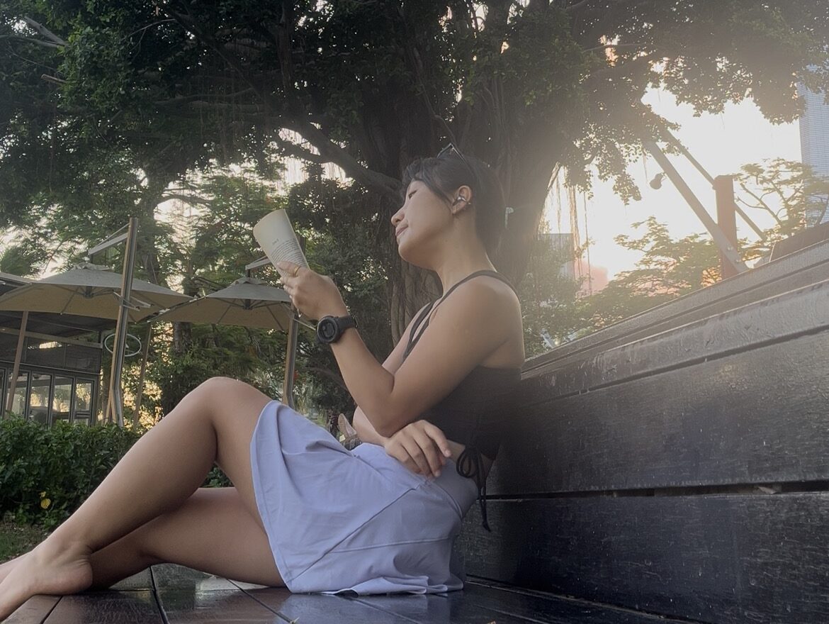 Falls reading a book under a tree at sunset, embracing a peaceful and intentional moment
