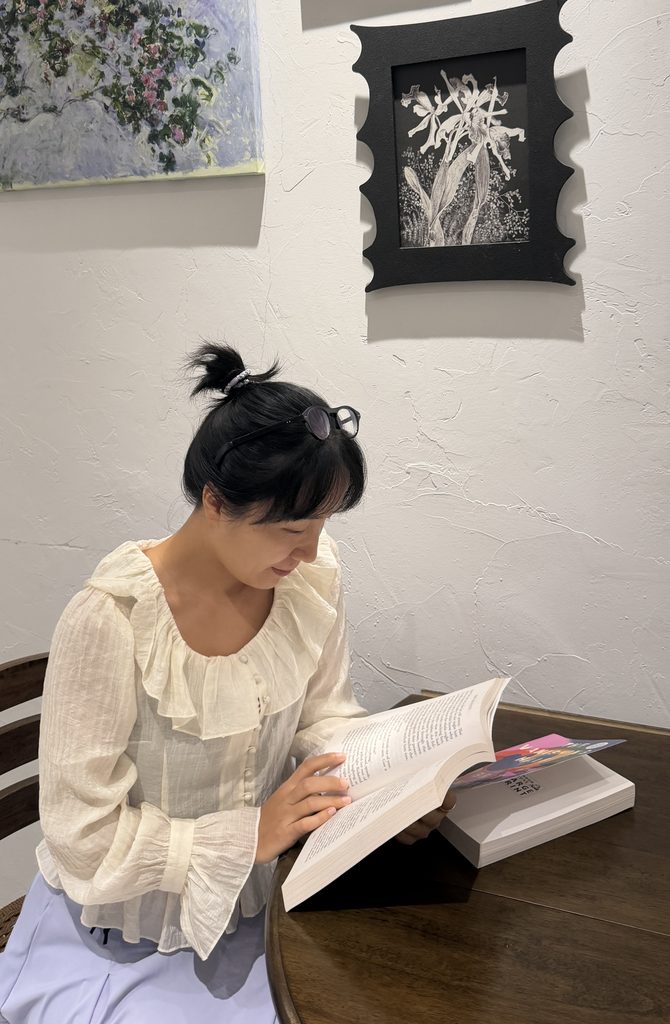 Falls sitting at a desk and reading The Vanishing Half book during a quiet reading session