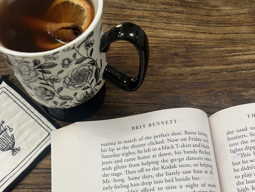 An open copy of The Vanishing Half book with a cup of tea beside it during a cozy reading moment