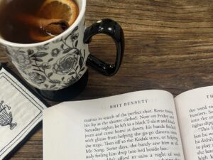 An open copy of The Vanishing Half book with a cup of tea beside it during a cozy reading moment