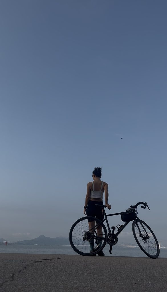 Falls standing by her bike on the coast on an autumn morning