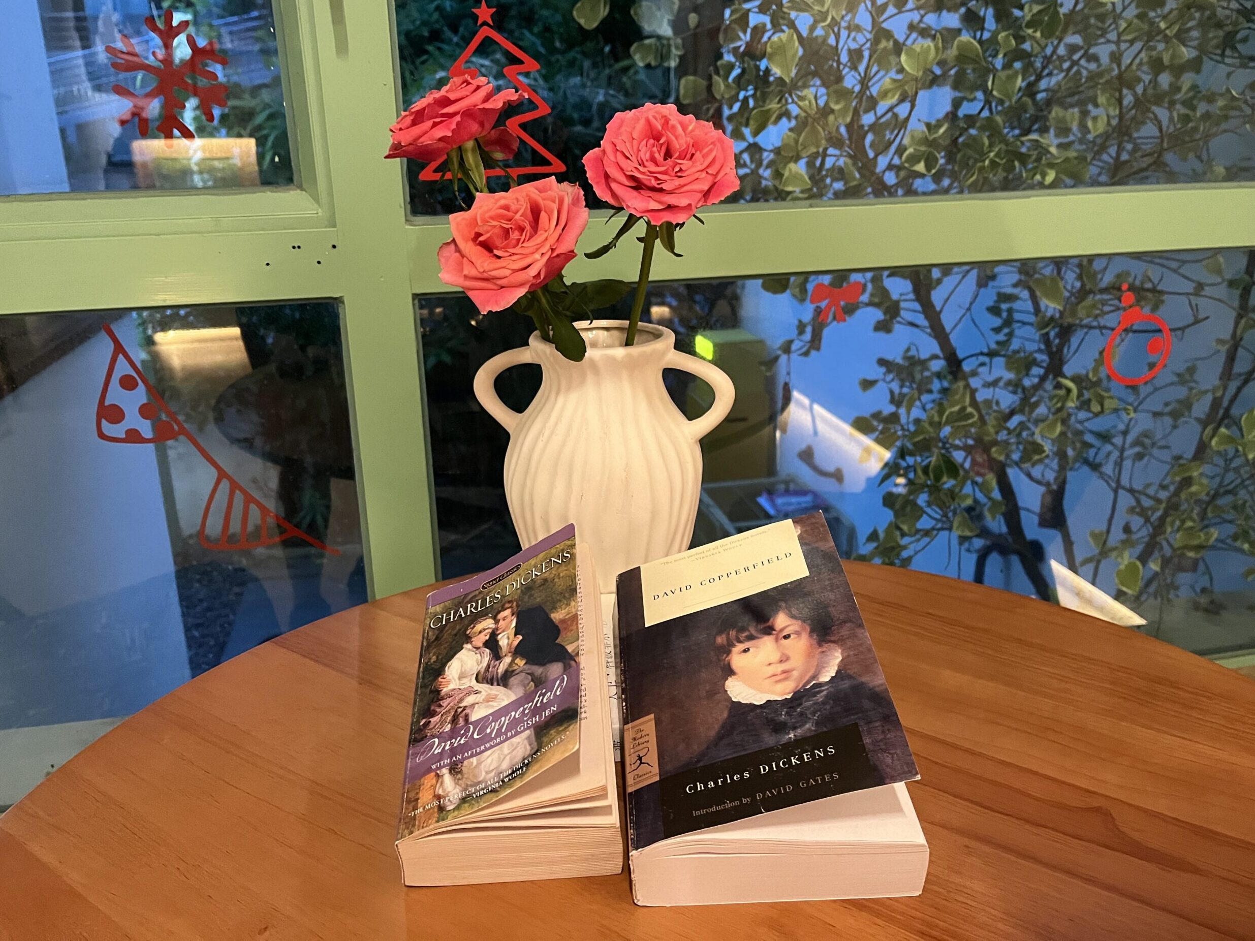 Two copies of David Copperfield on a table with a vase of two roses